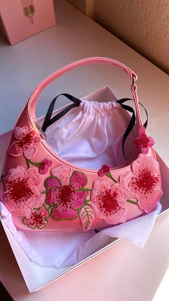 Handbag with floral embroidery displayed successful a acquisition box
