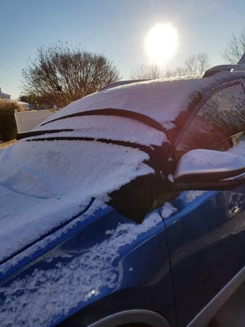 reviewer's car windshield with the cover on and full of snow