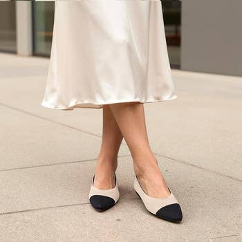 Person wearing a satin skirt and two-toned level  shoes lasting  connected  a sidewalk