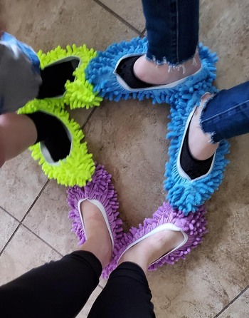 Three reviewers wearing green, blue, and purple slippers 