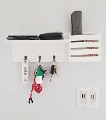 reviewer photo of the white wall shelf holding keys, wallets, and other small items