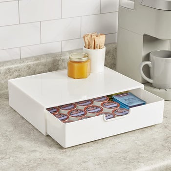A white plastic drawer pulled out to show coffee pods and tea packets