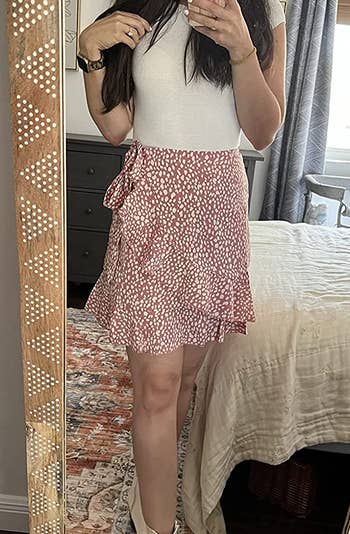 a reviewer taking a mirror selfie in the pink polka dot skirt