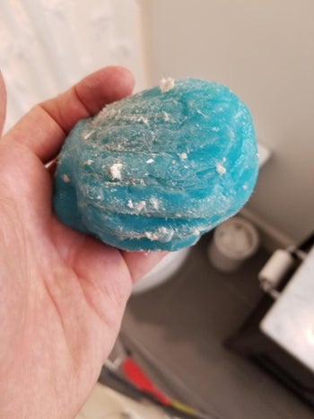 reviewer photo of them holding blue cleaning putty covered in dust