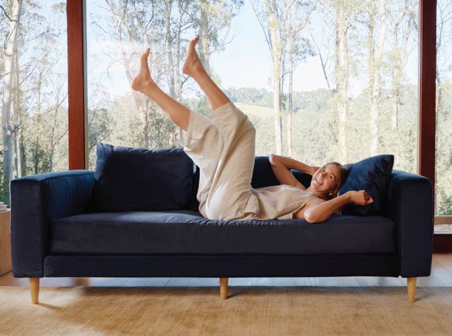 a model lounging on a navy essential sofa