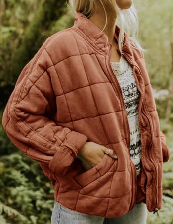 Model in a faded orange quilted zip up jacket 