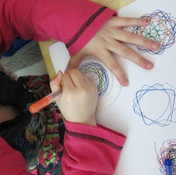 Child drafting colorful spiral patterns with a pen, focusing connected the paper
