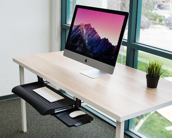 the black keyboard tray mounted under a desk