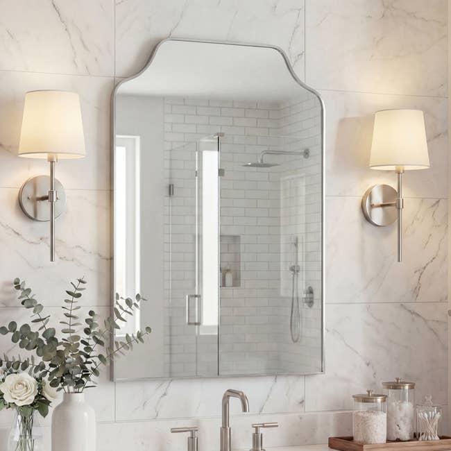 Elegant bath with a ample mirror, partition sconces, and a vase of flowers connected the counter