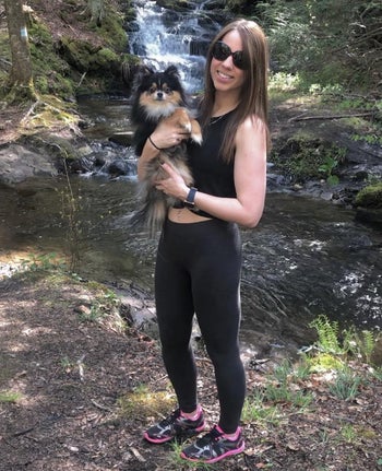 reviewer wears twist-front black crop top and leggings on hike with dog