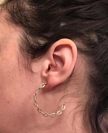reviewer photo of them wearing a gold paperclip hoop earring