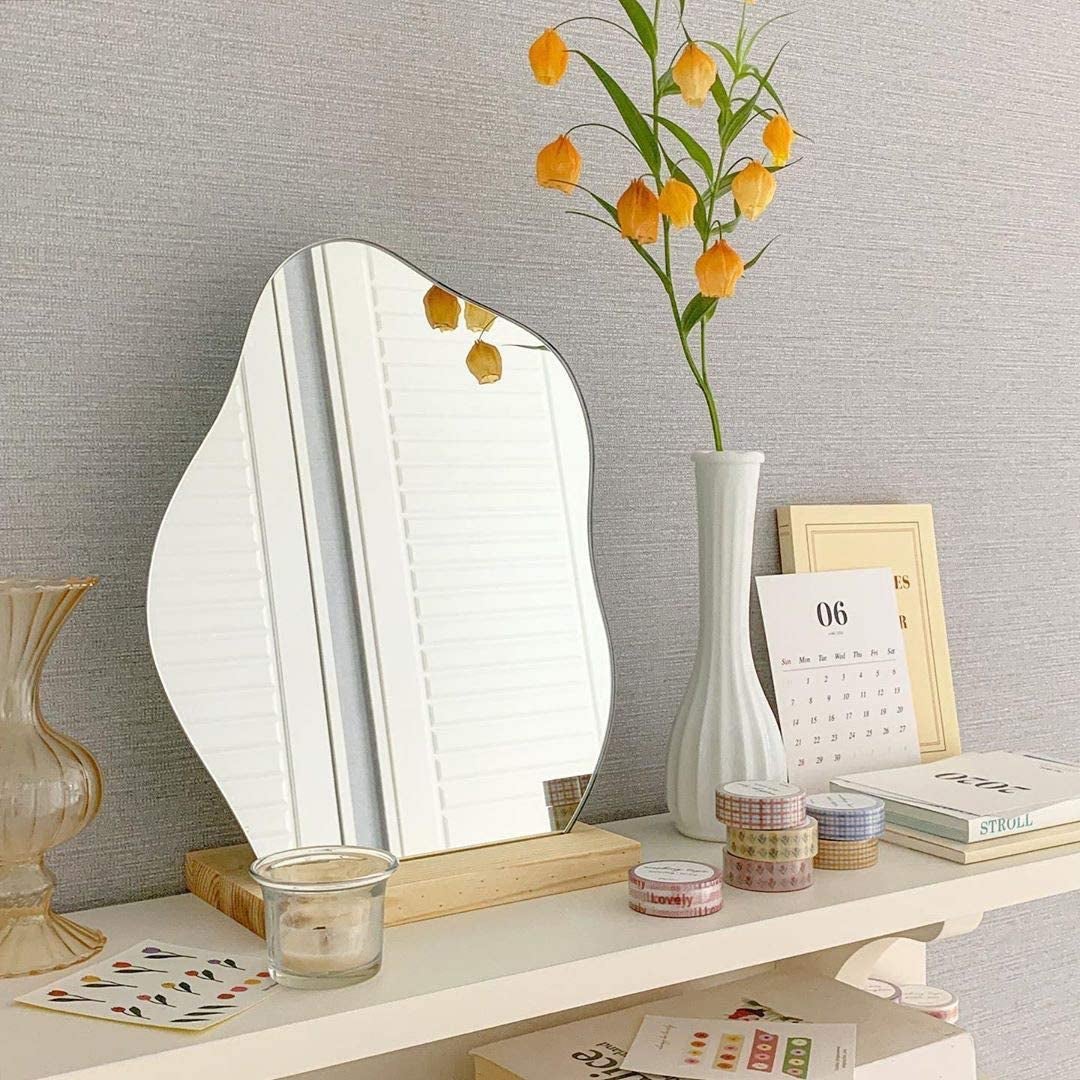 A small standing mirror in the shape of a cloud on a wooden base
