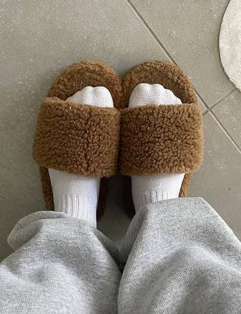 Person wearing fluffy beige slippers 