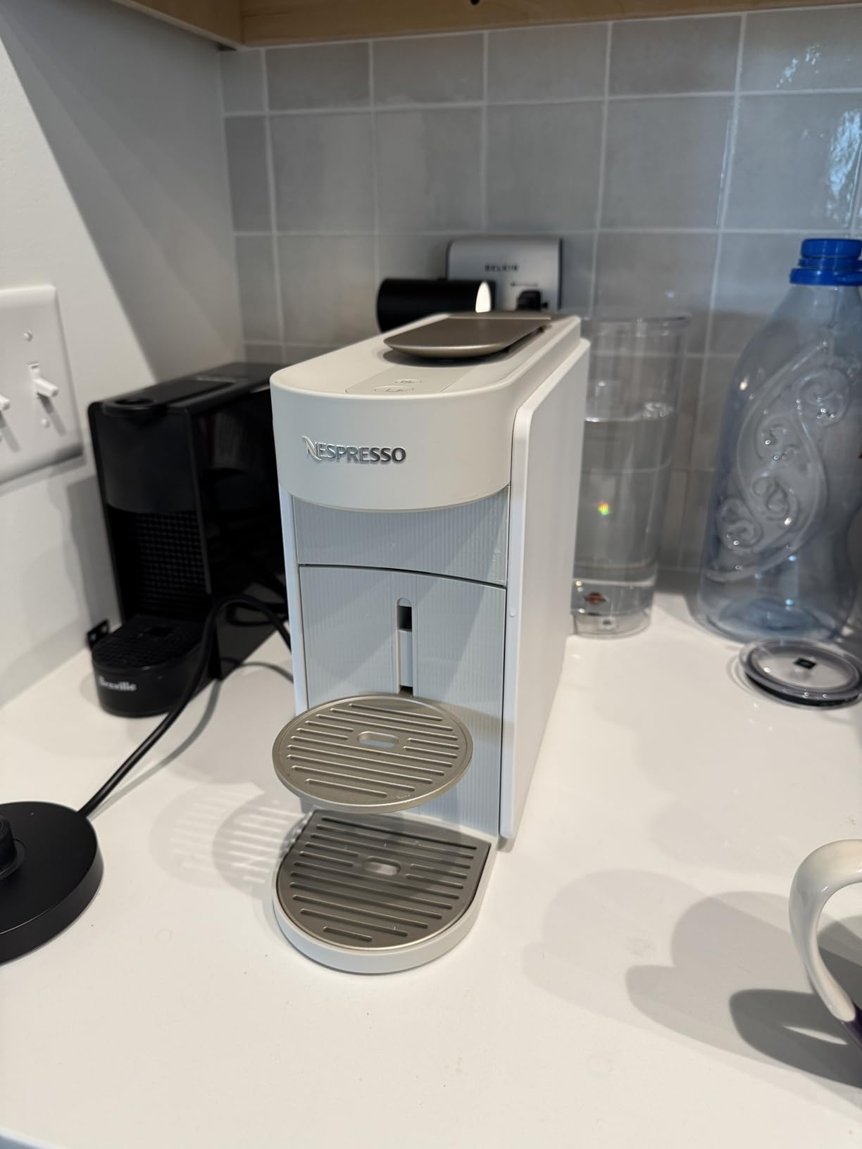 Nespresso java  instrumentality   connected  a room  antagonistic  with a h2o  vessel  and solid  nearby
