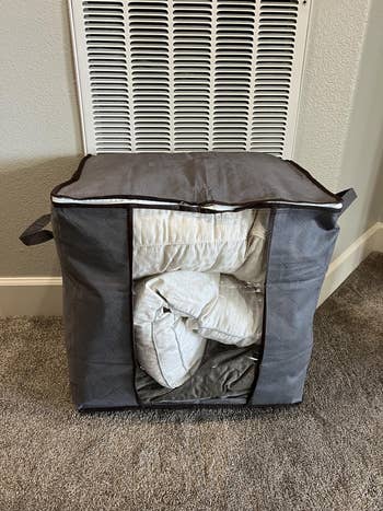 Quilt stored successful a large, grey cloth zippered retention container with handles, placed connected a carpeted level successful beforehand of a partition vent