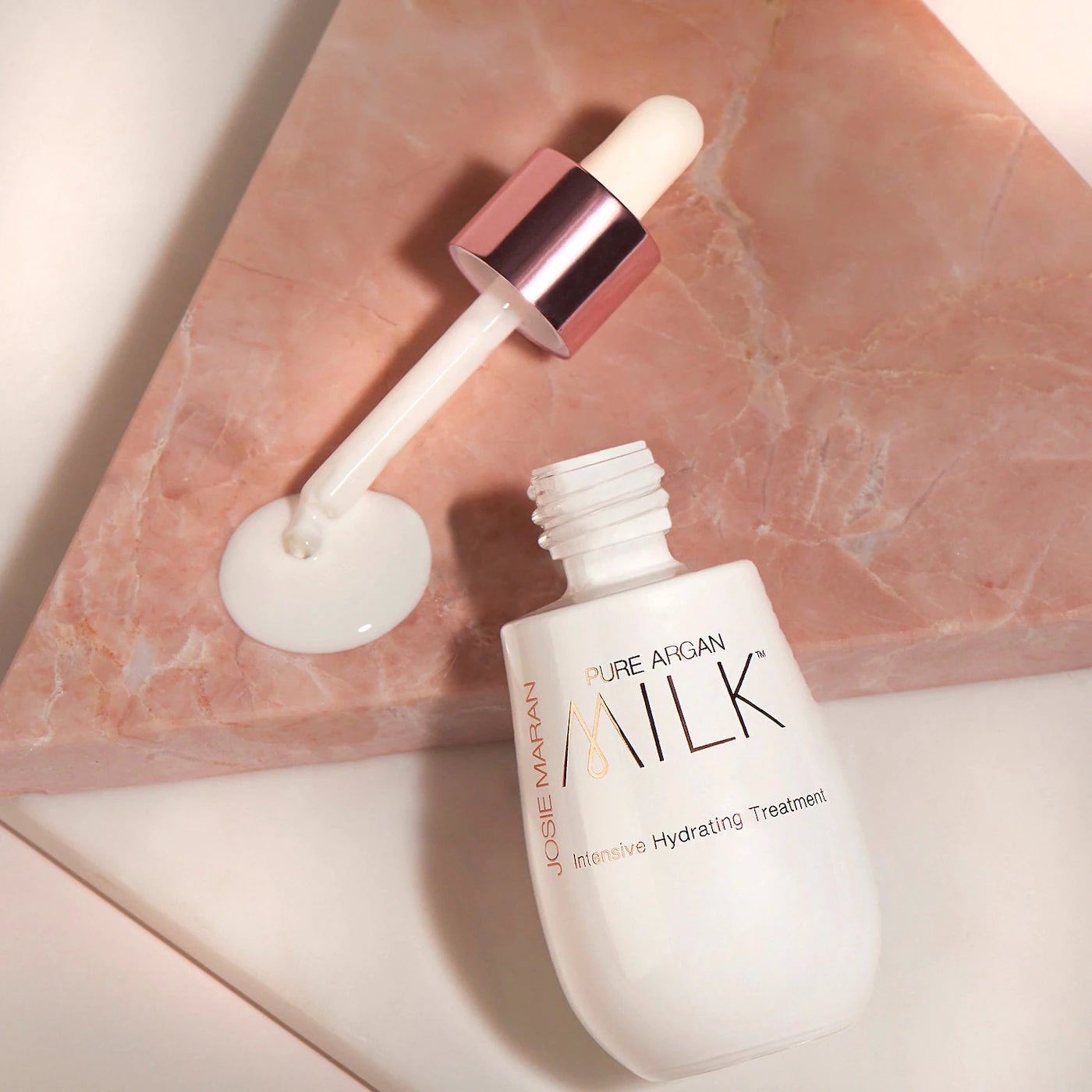 dropper and bottle of the argan milk treatment with product dripping out