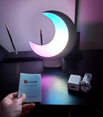 the moon glowing white with a bit of blue and pink in a dark room