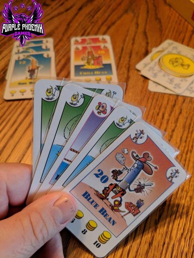 reviewer holding a hand of several bean cards