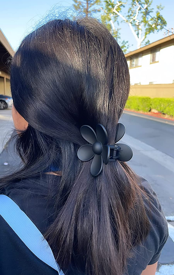 reviewer wearing the black flower claw in their hair