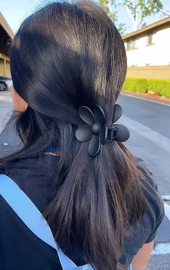 reviewer wearing the black flower claw in their hair