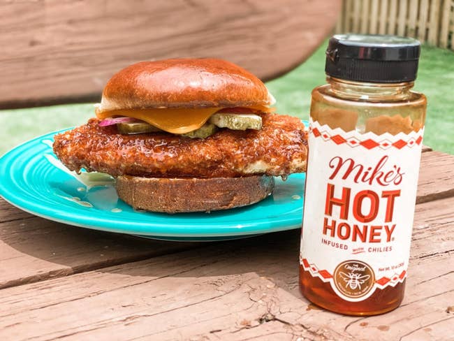 bottle of mike's hot honey next to a chicken sandwich 