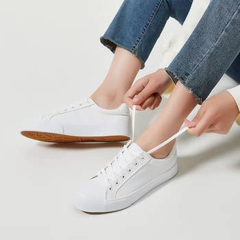 Person tying the laces connected  achromatic  sneakers