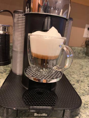 reviewer image of thee machine with a cup filled with frothed milk