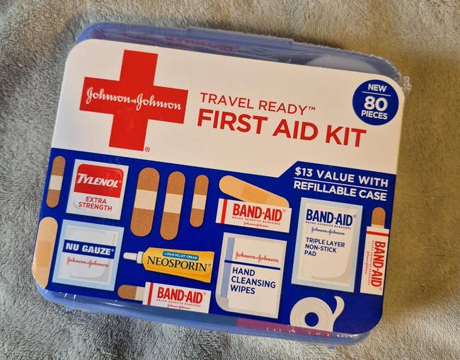 First assistance kit with Johnson & Johnson bandages, Neosporin, cleansing wipes, gauze, and symptom alleviation items. Advertised arsenic travel-ready with 80 pieces