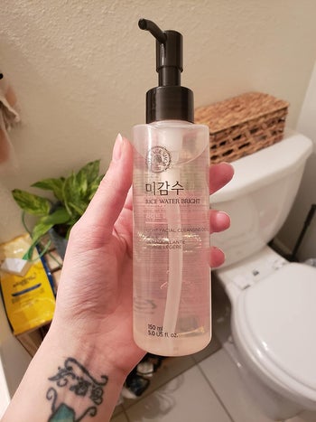 reviewer holding bottle of cleansing oil