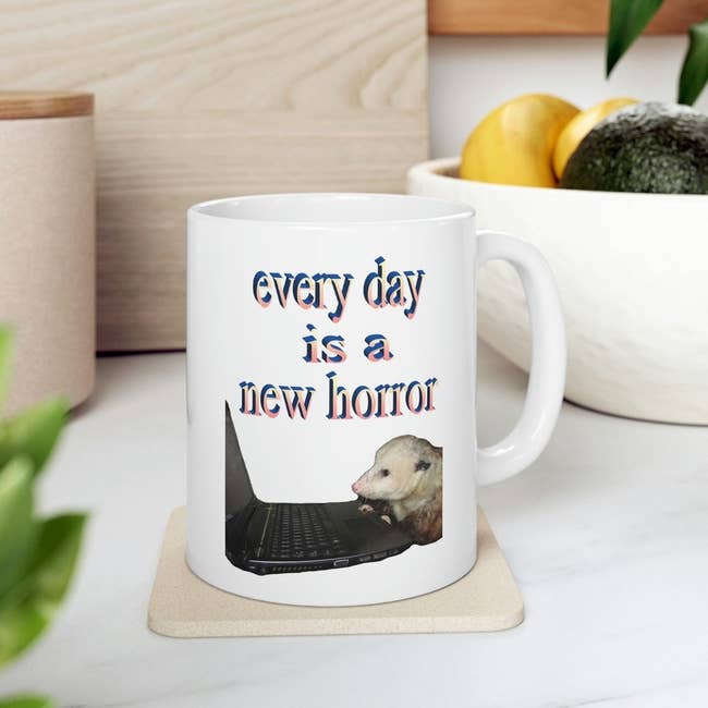 a white mug with a photoshopped image of a possum sitting at a laptop and there's word art font that says 