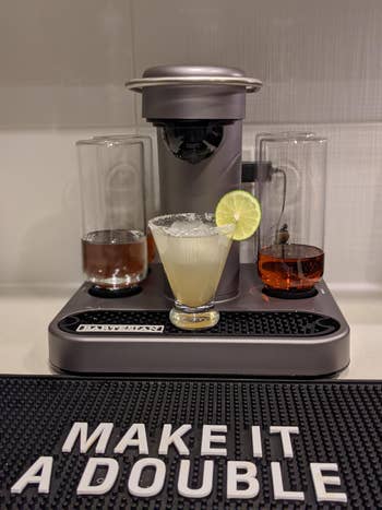 reviewer's machine set up with a freshly made cocktail and a bar mat that says 