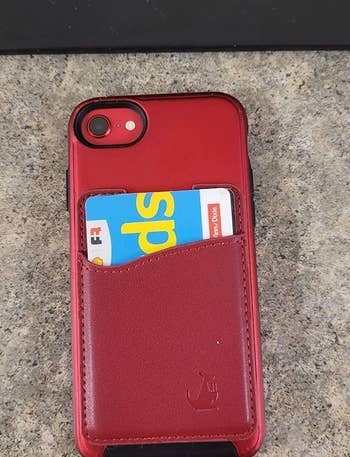 a reviewer photo of the red card wallet attached to the back of a phone 