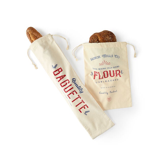 a baguette and bread loaf in their respective storage bags with drawstrings