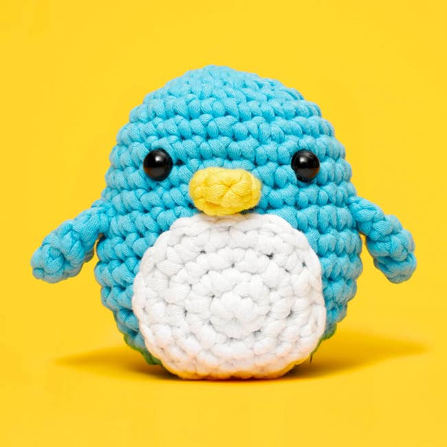small blue and white crocheted penguine in front of the kit