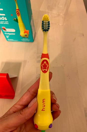 reviewer holding yellow toothbrush