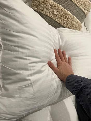 Reviewer pushing the pillow to show how plush it is