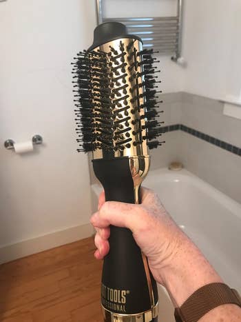 Reviewer holding black and gold hot straightening brush