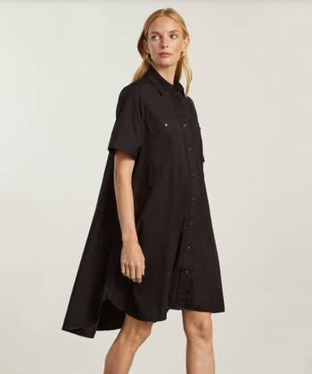 side view of model wearing the black shirtdress, showing how it flows in the back