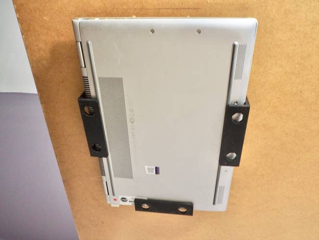 Laptop mounted upside down nether a table utilizing brackets