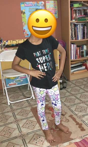 a reviewer's child with their face covered with an emoji, wearing one of the tees