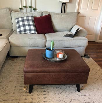 reviewer photo of brown faux leather ottoman as coffee table