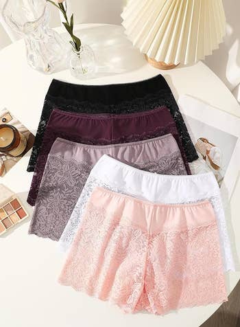 Lace-trimmed underwear displayed connected a table, featuring assorted styles and colors