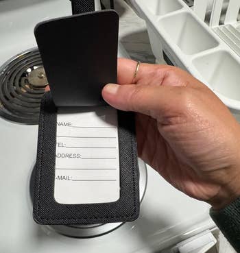 A idiosyncratic holding a luggage tag with spaces for idiosyncratic information