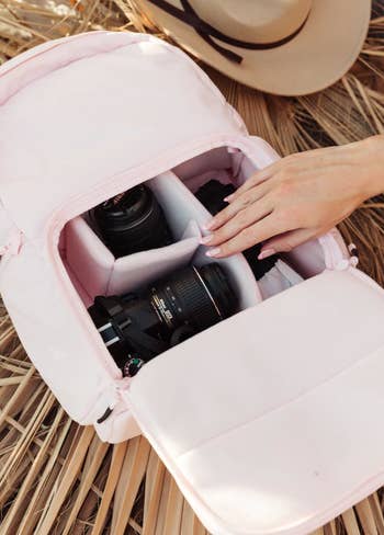 A model's hand placing camera accessories in the bag