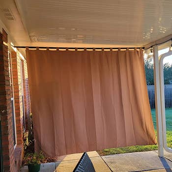 a reviewer photo of the curtain installed on a back patio, blocking the sun