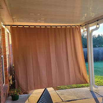 a reviewer photo of the curtain installed on a back patio, blocking the sun