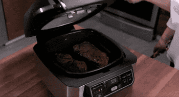 gif of model flipping steaks in the open Ninja air fryer