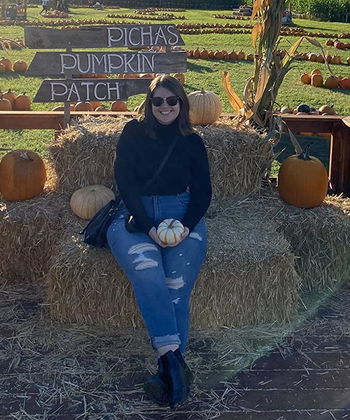 reviewer posing wearing black turtleneck in a pumpkin patch