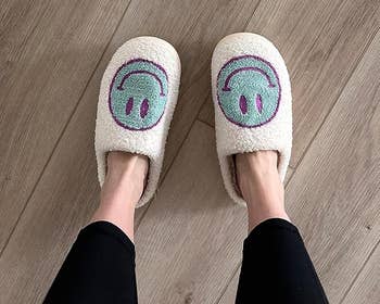 a reviewer wearing blue and purple smiley face slippers