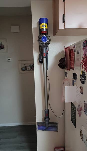 a reviewer shows the vacuum hanging in its wall holder